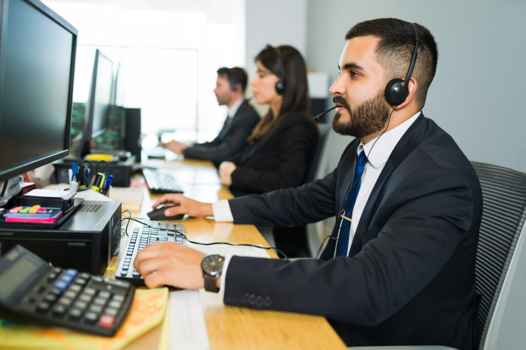Attractive latin executive offering customer service with headset offering tech support busy call center 1024x683